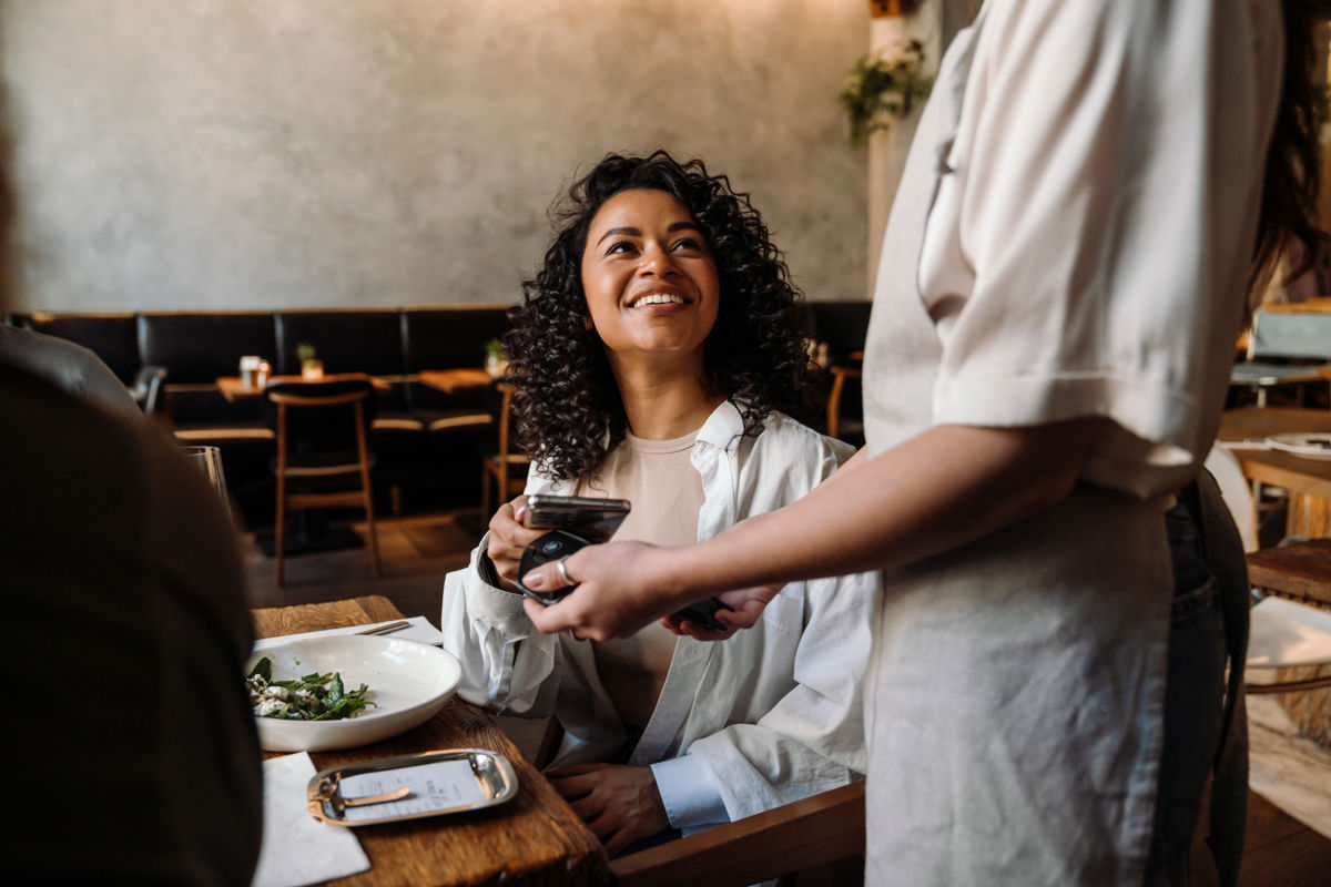 a woman smiling at a table with a waiter
